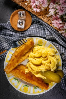 Kızarmış ekmek parçaları patates püresi ve salatalık turşusuyla servis ediliyor..