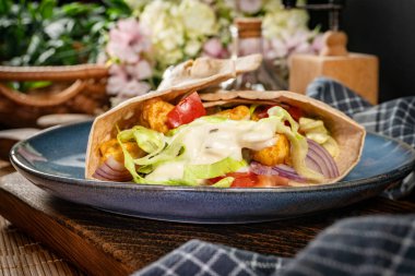 Kızarmış tavuk ve sebzeli salata. Baharatlı yaban turpu sosu ile sarılmış tortilla..