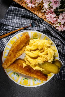 Kızarmış ekmek parçaları patates püresi ve salatalık turşusuyla servis ediliyor..