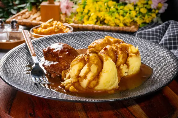 Traditional German braised pork cheeks in brown sauce served with mashed potatoes.