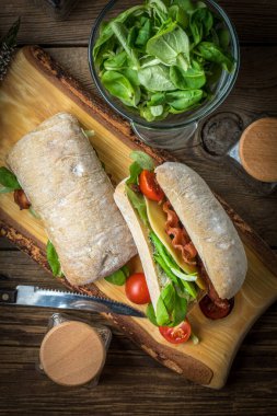 Ciabatta ahşap tahta üzerinde Roka Salatası, pastırma ve sarı peynirli sandviç. Üstten Görünüm.