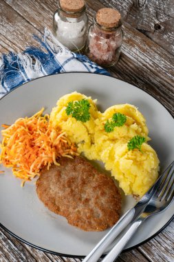 Patates püresi ve havuç salatasıyla servis edilen ev yapımı kıymalı pirzola..