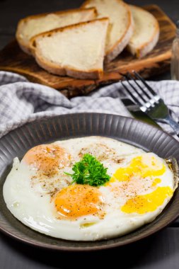 Gri arka planda kahvaltıda kızarmış yumurta ve ekmek..