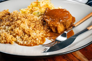 Sos soslu domuz budu, arpa ve lahana turşusu salatası. Sığ alan derinliği.