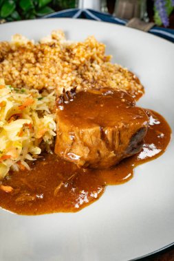 Sos soslu domuz budu, arpa ve lahana turşusu salatası. Sığ alan derinliği.