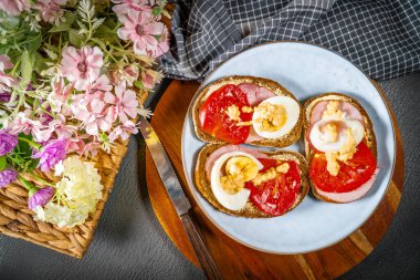 Jambonlu sandviç, yumurtalı ve domatesli mavi tabak.