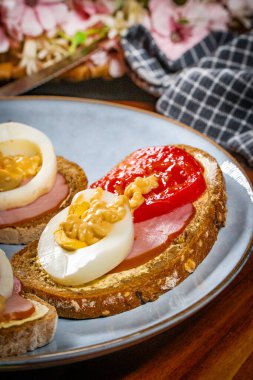 Jambonlu sandviç, yumurtalı ve domatesli mavi tabak.