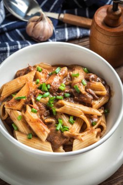 Ahşap masa üzerinde kase domuz soslu makarna penne.