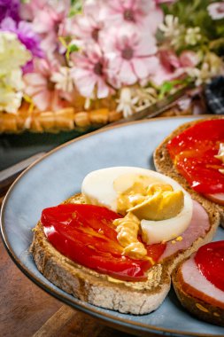 Jambonlu sandviç, yumurtalı ve domatesli mavi tabak.