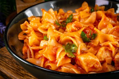 Domates soslu erişteli tavuk parçaları. Sığ alan derinliği.