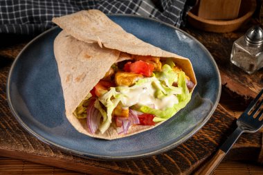 Kızarmış tavuk ve sebzeli salata. Baharatlı yaban turpu sosu ile sarılmış tortilla..