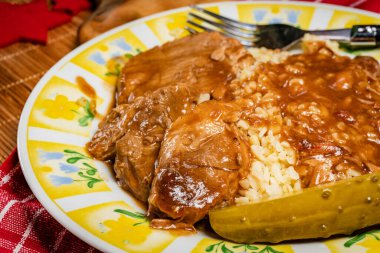 Kendi sosunda domuz buğulama ve salatalık turşusuyla servis edilir..