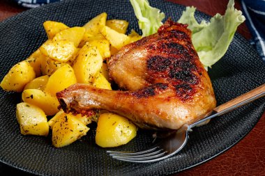 Appetizing baked chicken leg quarter with browned skin served with crispy fries for dinner.
