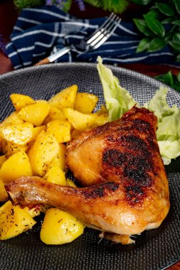 Appetizing baked chicken leg quarter with browned skin served with crispy fries for dinner.