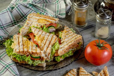 Panini sandviçle jambon, domates, marul bir plaka üzerinde.