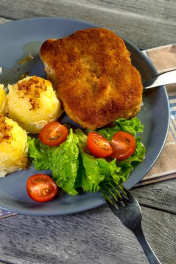 Pirzola, domuz jambonlu, haşlanmış patates ve tabakta salata..