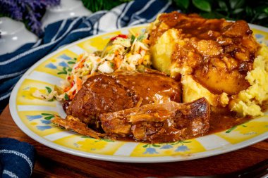 Soslu domuz budu. Patates püresi ve salata ile servis edilir..