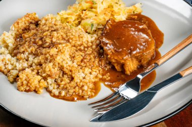 Sos soslu domuz budu, arpa ve lahana turşusu salatası. Sığ alan derinliği.