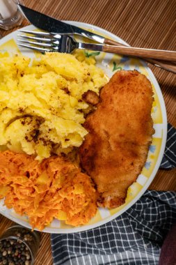 Kızarmış tavuk göğsü fileto haşlanmış patates ve havuç salatası ile servis edilir..