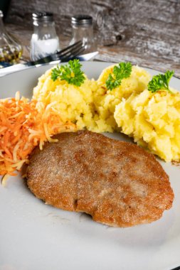 Patates püresi ve havuç salatasıyla servis edilen ev yapımı kıymalı pirzola..
