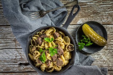 Tahta masaya dökme demir tavada sığır soslu İtalyan makarna kabukları. Üst görünüm.