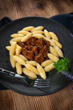 Soslu sığır eti yahnisi, patates köftesiyle servis edilir..