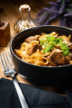 Tahta masada biftek soslu Tagliatelle yosunları. Koyu ışık.