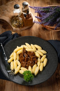 Soslu sığır eti yahnisi, patates köftesiyle servis edilir..