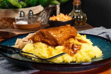 Patates püresi ve lahana turşusuyla servis edilen baharatlı soslu domuz pirzolası. Sığ alan derinliği.