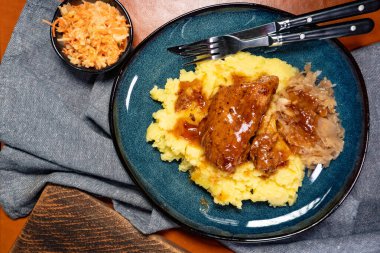 Patates püresi ve lahana turşusuyla servis edilen baharatlı soslu domuz pirzolası. Sığ alan derinliği.