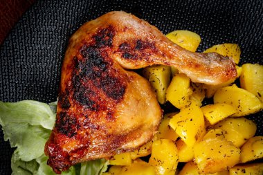 Appetizing baked chicken leg quarter with browned skin served with crispy fries for dinner.