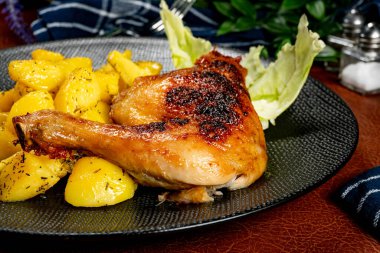 Appetizing baked chicken leg quarter with browned skin served with crispy fries for dinner.