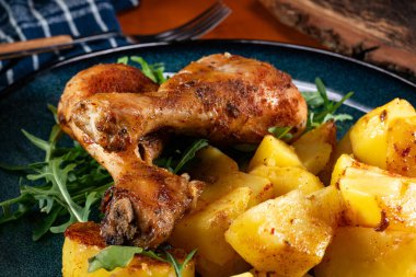 Fırında tavuk budu ve patates. Yüzeyin derinliği. Koyu ışık.