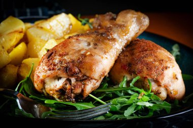 Fırında tavuk budu ve patates. Yüzeyin derinliği. Koyu ışık.