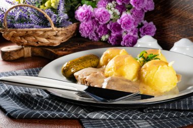 Patates püresi ve salatalık turşusuyla servis edilen hardal-yaban turpu soslu haşlanmış domuz dilleri..