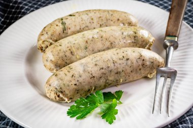 Bir tabakta üç pişmiş beyaz sosis. Seçici odak.