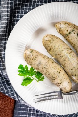 Bir tabakta üç pişmiş beyaz sosis. Seçici odak.