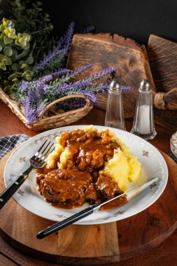 Patates püresi ve salatayla servis edilen soslu domuz budu..