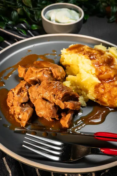 Sos ve patates püresiyle servis edilen haşlanmış hindi eti. Sığ alan derinliği.