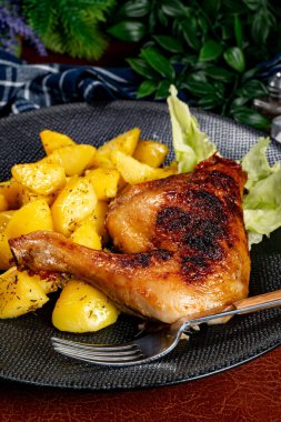Appetizing baked chicken leg quarter with browned skin served with crispy fries for dinner.