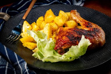 Appetizing baked chicken leg quarter with browned skin served with crispy fries for dinner.