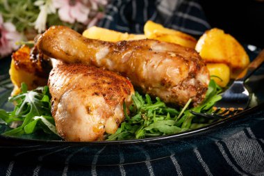 Fırında tavuk budu ve patates. Yüzeyin derinliği. Koyu ışık.