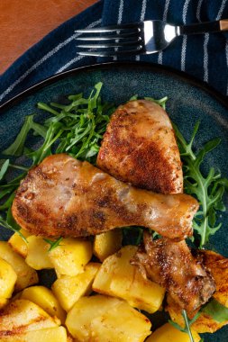 Fırında tavuk budu ve patates. Yüzeyin derinliği. Koyu ışık.