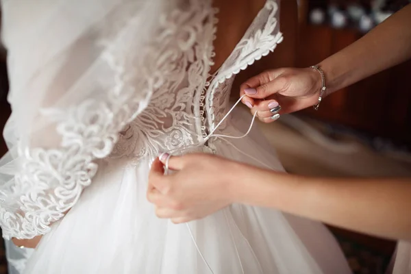 婚礼上的目击者帮助新娘在婚纱上系好了紧身胸衣 女孩的手把鞋带紧固在衣服上 有花边樱桃的白色礼服 — 图库照片