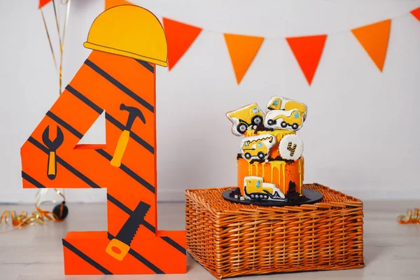 小さな男の子のための大きなオレンジの誕生日ケーキ 安全ヘルメットと大きな4の近くの木製のスタンドにクッキーの形で建設機械で飾られました — ストック写真