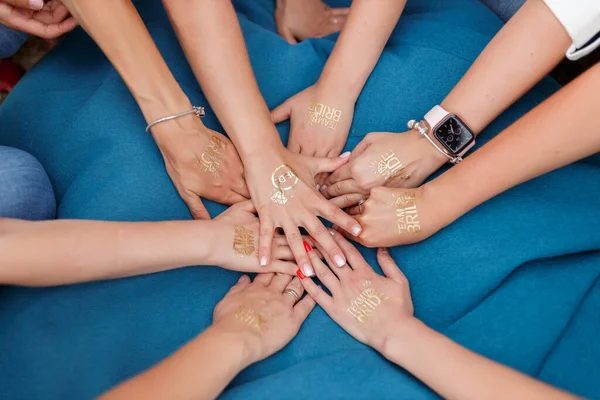 Hands of young girls with manicure without faces folded in the center with the inscriptions team of the bride in gold letters. bachelorette party celebration