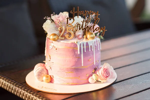 大きな層状ピンクの女の子の誕生日ケーキと黄金の数字25と碑文はテーブルの上に素朴なスタンドに花やケーキで飾られました — ストック写真