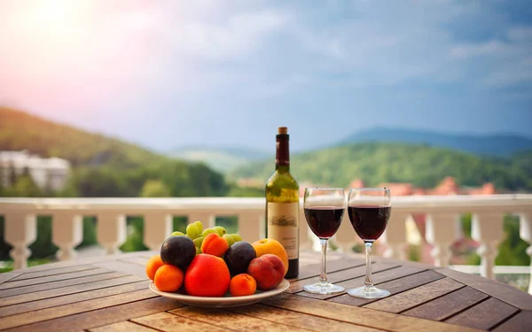 red wine, fruit and wine are on the table for a romantic date