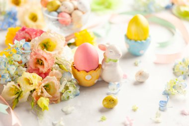 Renkli yumurtalar, şekerler ve çiçek dolu Paskalya arkaplanınız kutlu olsun. Tatil için masa dekorasyonu.