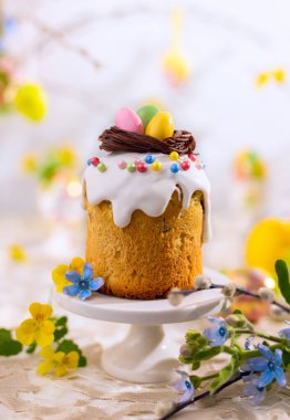 Çikolata yuvalı geleneksel Paskalya keki ve paskalya yumurtası şekeri. Bahar çiçekleriyle süslenmiş Paskalya hediyeleri.